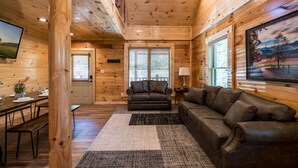 Un interior de madera con un sofá, una mesa de comedor y un televisor.