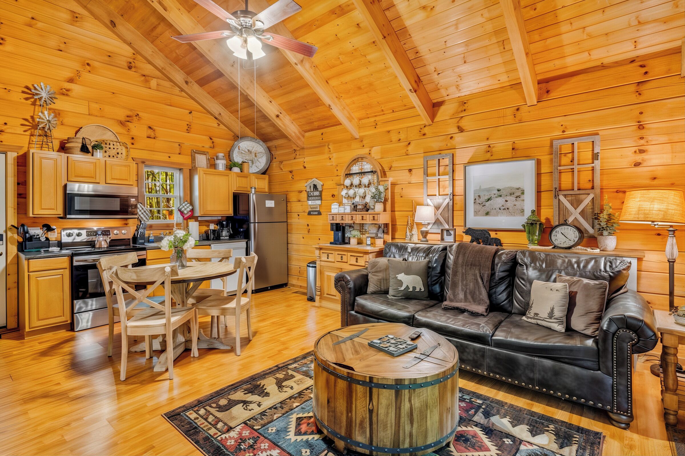 L’intérieur chaleureux d’un chalet en rondins comprend un coin repas, une cuisine et un salon aménagé avec des canapés en cuir et des éléments décoratifs en bois.