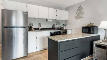 Una cucina moderna con elettrodomestici in acciaio inossidabile, mobili bianchi e un piano di lavoro in granito.