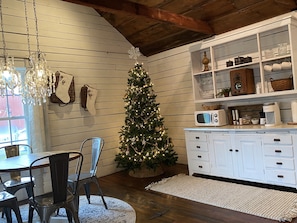Une cuisine chaleureuse avec des murs en bois, un meuble blanc, un sapin de Noël et un lustre.