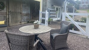 A patio with wicker furniture, a round table, and a white fence.