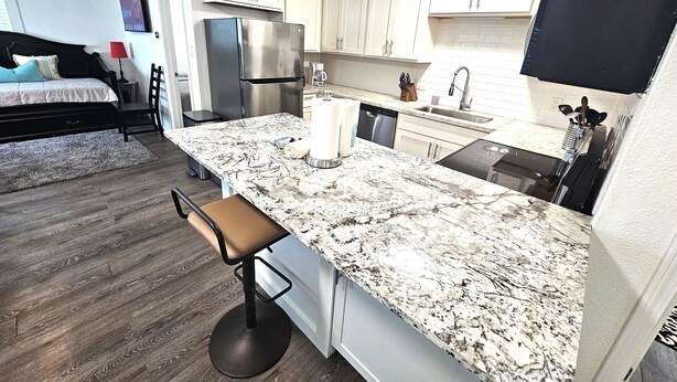 A modern kitchen with a large island, built-in appliances, and a dining area with a bar stool. - "Molly”-Sea Isle w/Gulf View, Pool,yard,2 kayaks, 8min walk 2beach, Dog friendly (Galveston)