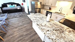 A modern kitchen with granite countertops, stainless steel appliances, and white cabinetry. - "Molly”-Sea Isle w/Gulf View, Pool,yard,2 kayaks, 8min walk 2beach, Dog friendly (Galveston)