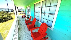 A porch with red Adirondack chairs and a white railing. - "Molly”-Sea Isle w/Gulf View, Pool,yard,2 kayaks, 8min walk 2beach, Dog friendly (Galveston)