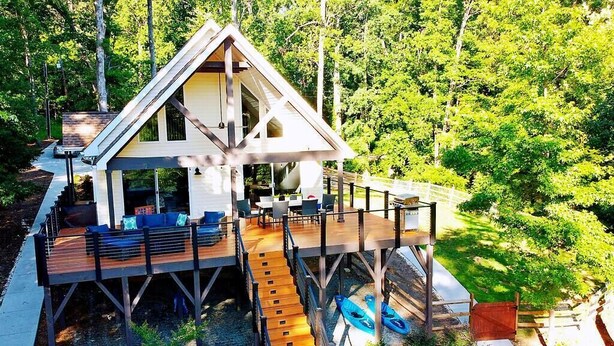 A wooden deck with outdoor seating, a boat, and a natural forest backdrop. - Lakefront retreat for family, friends & fun! (Lake Norman of Catawba)