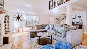 A spacious living room with a large window, a staircase, and a bookshelf. - Lakefront retreat for family, friends & fun! (Lake Norman of Catawba)