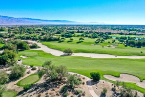 Un campo de golf con varios hoyos, búnkeres de arena y una vista despejada del paisaje circundante.