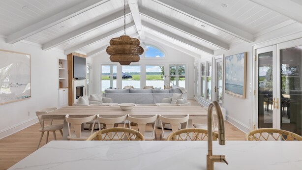 A spacious kitchen with a large island, white cabinetry, and a view of a lakeside landscape. - VRBO 2025 Rental of the Year | Folly Riverfront Retreat w/ Dock & Pool (Folly Beach)