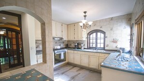 A spacious kitchen with a large island, a built-in oven, and a window with decorative tiles.