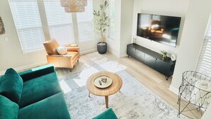 A modern living room with a large green sofa, a coffee table, a TV, and a black entertainment unit. - 4 BEDROOM MODERN HOME, FREE PARKING, A/C, W/D,WIFI (Westminster)