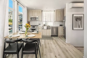 Cozinha moderna com área de refeições, janelas amplas e vista para o exterior.