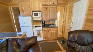 A compact cabin with a kitchenette, two leather sofas, and a wooden ceiling. - Log Cabin by ND Badlands (Grassy Butte)