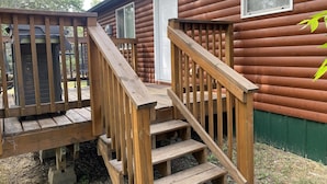 A wooden staircase leading to a cabin with a door and windows. - Log Cabin by ND Badlands (Grassy Butte)