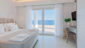 A modern hotel room with a bed, a desk, and a view of the sea. - seafront brand new luxury villa swimming pool -ideal for families, free transfer (Μακρύ-Γιαλός)