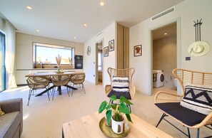 A modern living room with a dining area, a kitchen, and a laundry room.