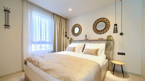 A modern bedroom with a large bed, a bedside table, a mirror, and a hanging plant. - Villa QUARNARO with heated pool (Omišalj)