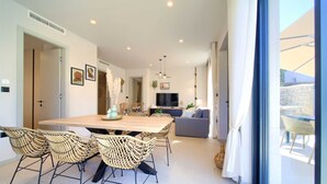 A spacious living area with a wooden dining table, wicker chairs, a grey sofa, and a TV. - Villa QUARNARO with heated pool (Omišalj)