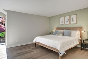 A bedroom with a bed, bedside tables, and wall-mounted artwork.
