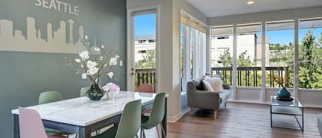 Ein modernes Wohnzimmer mit Essbereich, großen Fenstern und einer Wandmalerei der Skyline von Seattle.