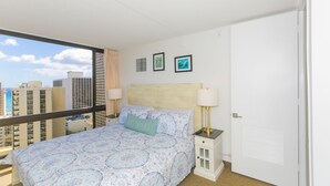 Ett hotellrum med en stor säng, två sängbord, ett litet bord och utsikt över stadsbilden.