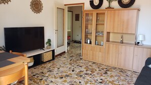 A living room with a TV, wooden cabinet, and a tiled floor. - Charming Perledo Retreat with Lake View, Balcony & Parking (Perledo)