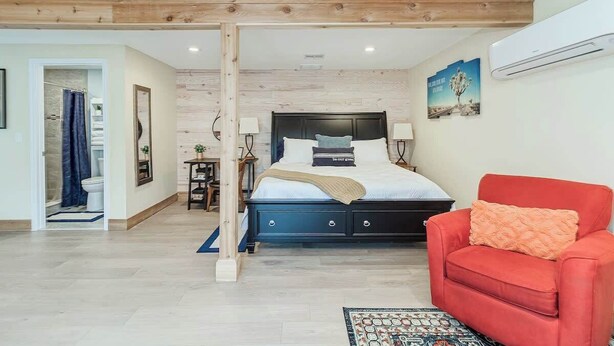 A bedroom with a bed, a red chair, and a wooden ceiling. - Studio Apartment w/ King Bed & Kitchenette (Lakeland)