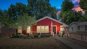 A red house with a porch, a flag, and a small garden. - La Casa Roja - Pet-Friendly - 3BR Home - Walk to Castle & Downtown Waco (Waco)