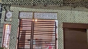 Un bâtiment à deux étages doté d’un balcon, de grilles décoratives aux fenêtres et d’une grande porte de garage.