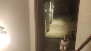 Un couloir étroit avec un escalier menant à une pièce sombre.