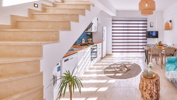 A modern interior with a staircase leading to a kitchen, a dining area with a TV, and a living room with a coffee table and a plant. - Villa Ay (Kas)