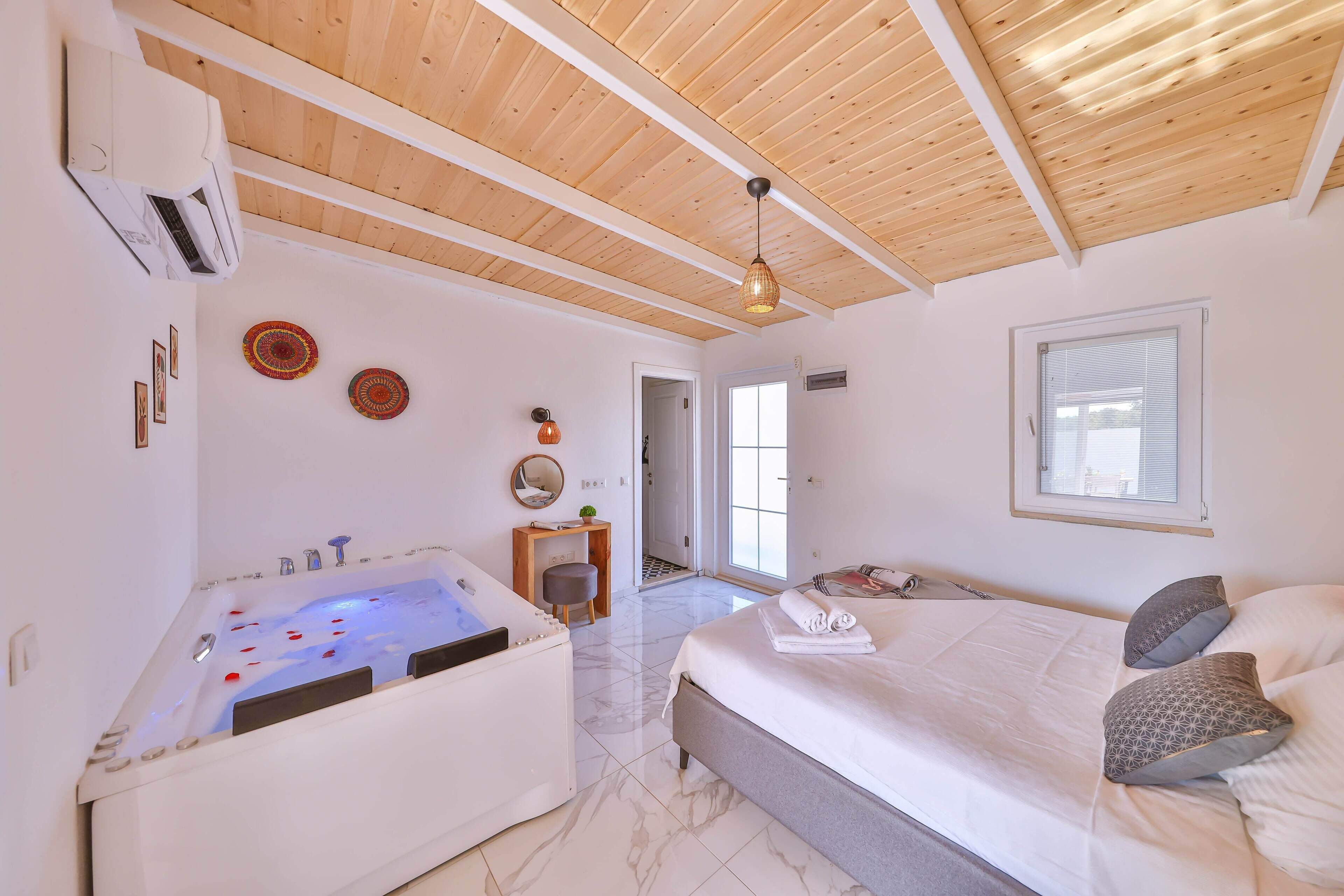 Ein modernes Schlafzimmer mit einem großen Bett, einer Badewanne und einer Holzbalkendecke.