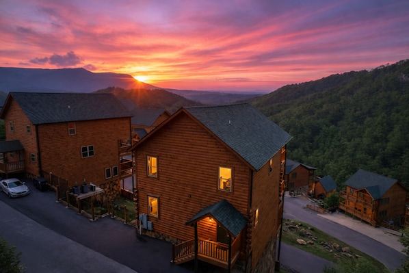 A log cabin hotel with multiple buildings, a driveway, and a car parked outside.