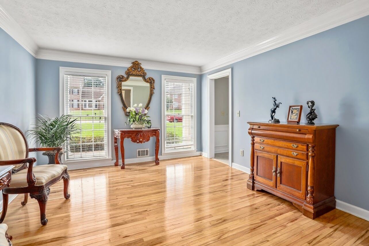 Una habitación con piso de madera, un espejo grande, un aparador de madera y una silla.