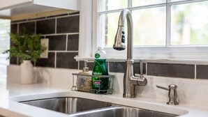 Une cuisine équipée d’un évier en acier inoxydable, d’un robinet moderne et d’une bouteille de liquide vaisselle Palmolive posée sur le comptoir.