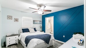 Ein Schlafzimmer mit Bett, Nachttisch, Kommode und Deckenventilator.