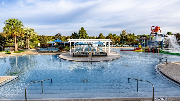 Una piscina con tobogán y zona de estar techada.