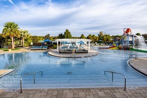 Une piscine avec un toboggan et un espace de repos abrité.