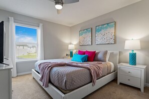 Ein Schlafzimmer mit einem Bett, Nachttischen, einem Deckenventilator und Bildern an der Wand.