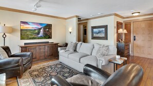 Ein Wohnzimmer mit einer Couch, Ledersesseln, einem Fernseher und einem Kamin.