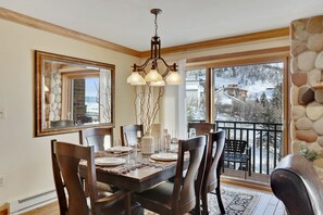 A dining room with a wooden table set for six, a chandelier, and a large mirror.