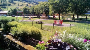 Un parque con juegos infantiles, mesas de picnic y un área cercada con flores.
