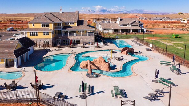 A resort with a large pool area, multiple buildings, and a mountainous backdrop.