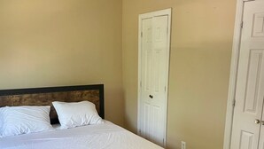 A bedroom with a bed, wooden floor, beige walls, and white doors. - The Village - Private apartment w/ parking 5 min walking (Mamaroneck)