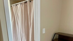A room with a wooden floor, a beige wall, a wooden dresser with drawers, and a shower curtain. - The Village - Private apartment w/ parking 5 min walking (Mamaroneck)