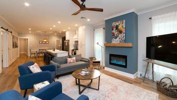 A modern living room with a fireplace, blue sofas, a coffee table, and a TV.