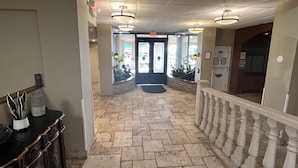 A hotel lobby with a stone floor, a reception desk, and a staircase with a balustrade. - Ocean View Modern Remodeled in Pirates Cove, Full Stove, Balcony Closed. (Daytona Beach Shores)
