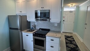 A modern kitchen with white cabinets, stainless steel appliances, and a black countertop. - Ocean View Modern Remodeled in Pirates Cove, Full Stove, Balcony Closed. (Daytona Beach Shores)