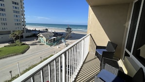 A balcony with outdoor furniture, a view of the beach, and a lifeguard tower. - Ocean View Modern Remodeled in Pirates Cove, Full Stove, Balcony Closed. (Daytona Beach Shores)