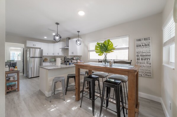 A modern kitchen with white cabinets, stainless steel appliances, and a central island with stools.