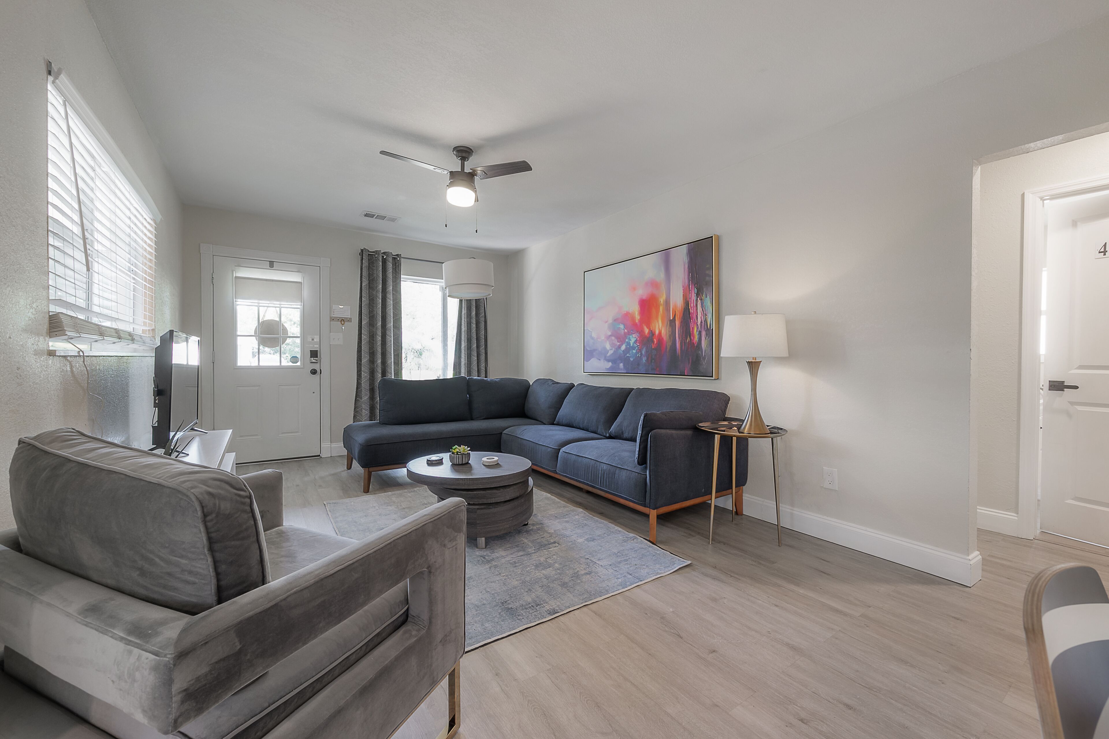 A modern living room with a grey sectional sofa, a round coffee table, and a ceiling fan.